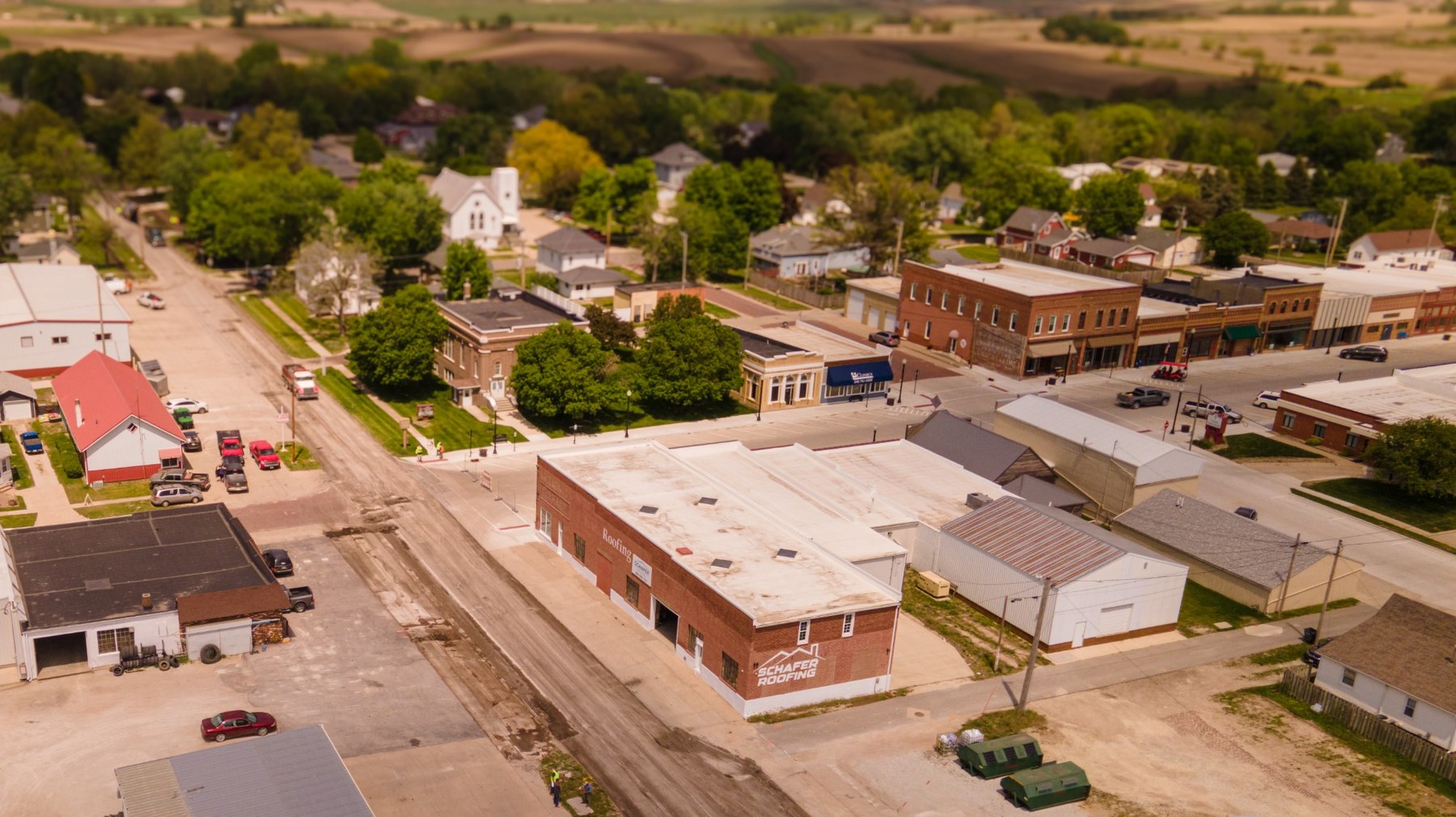 Aerial drone photo overlooking a small Iowa downtown, rooftops, streets, and surrounding rural landscape